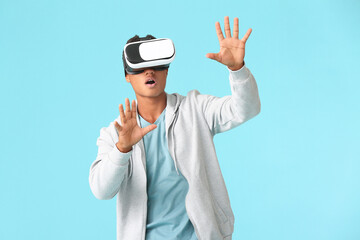 Teenage African-American boy with virtual reality glasses on color background