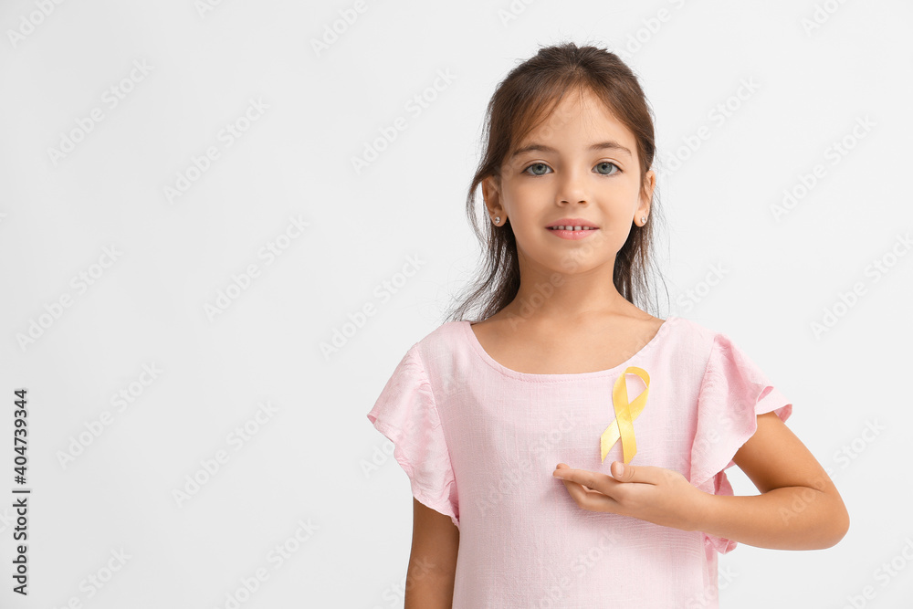 Little girl with golden ribbon on light background. Childhood cancer awareness concept Little girl with golden ribbon on light background. Childhood cancer awareness concept