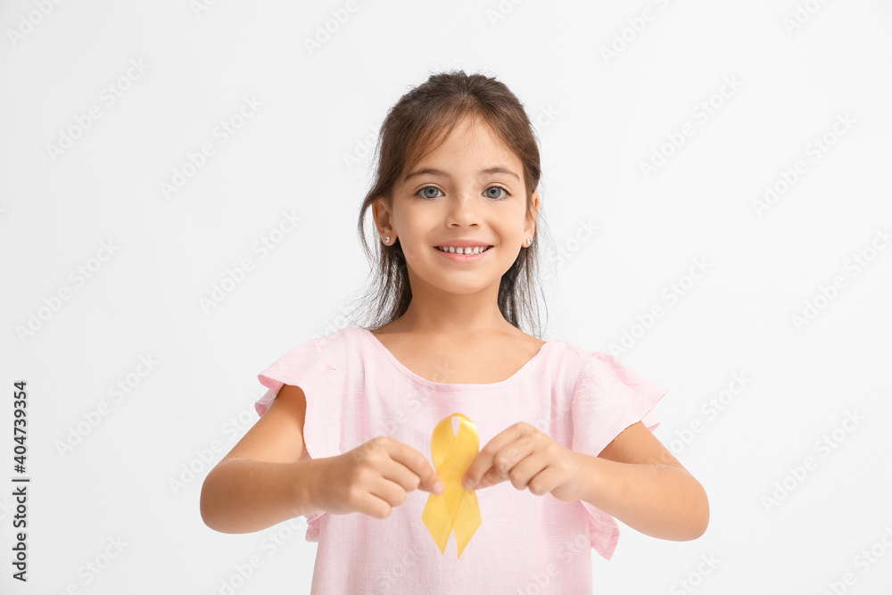 Little girl with golden ribbon on light background. Childhood cancer awareness concept Little girl with golden ribbon on light background. Childhood cancer awareness concept