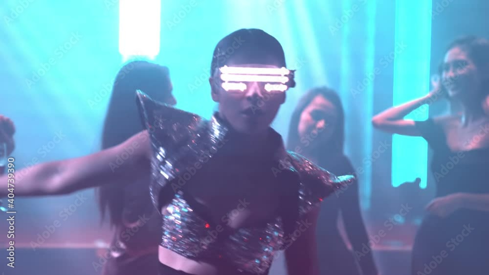 Group of people dance in disco night club to the beat of music from DJ on stage . New year night party and nightlife concept .