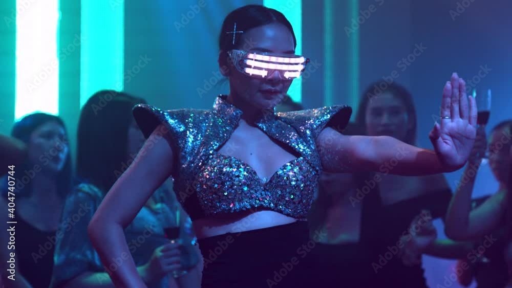 Group of people dance in disco night club to the beat of music from DJ on stage . New year night party and nightlife concept .