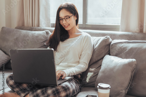 Young woman working on laptop and sitting at home. Beautiful busineeswoman working at home and smiling. Working at home during Coronavirus or Covid-19 quarantine.