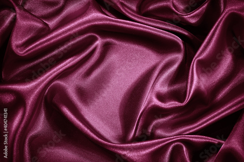 Red purple silk satin background. Shiny fabric with wavy soft pleats. Beautiful fabric background with empty space for your product and design.