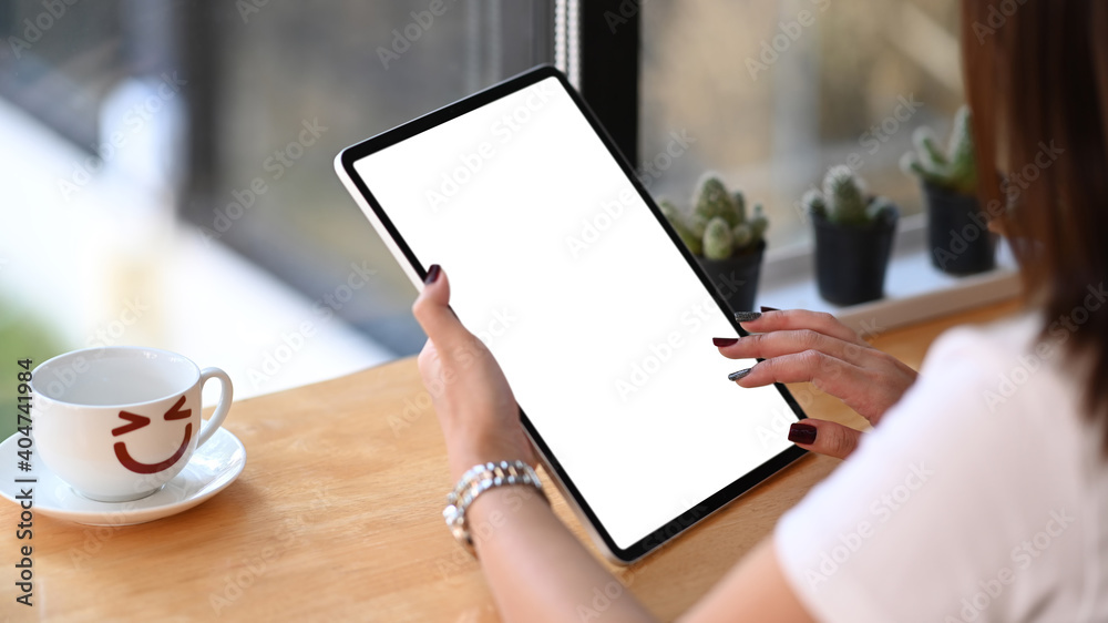Close up view young woman using digital tablet with blank screen at her workstation. Close up view young woman using digital tablet with blank screen at her workstation.