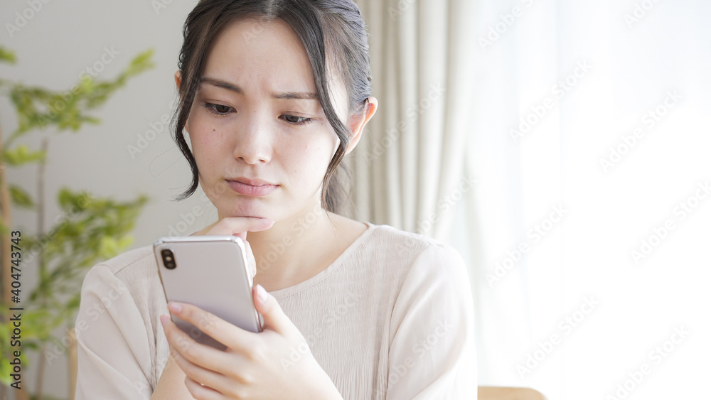 リビングでスマートフォンを見る若い女性 リビングでスマートフォンを見る若い女性