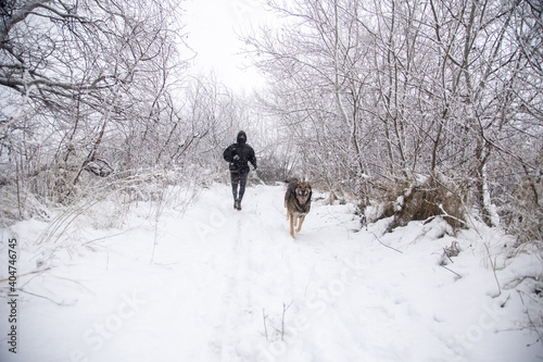 man running with dog in snowy landscape