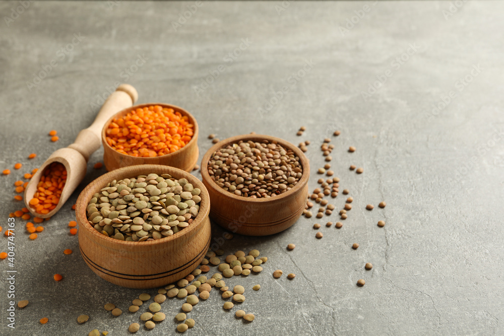 Scoop and bowls with different legumes on gray background Scoop and bowls with different legumes on gray background