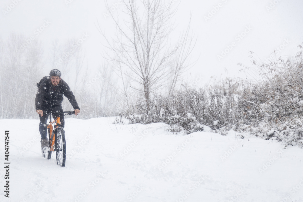 man on orange mountain bike in snowy landscape