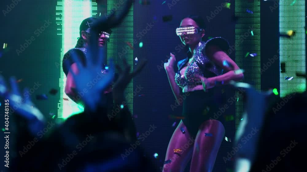 Group of people dance in disco night club to the beat of music from DJ on stage . New year night party and nightlife concept .