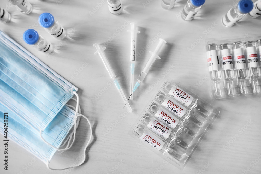 Vaccine for immunization against COVID-19, medical masks and syringes on table Vaccine for immunization against COVID-19, medical masks and syringes on table