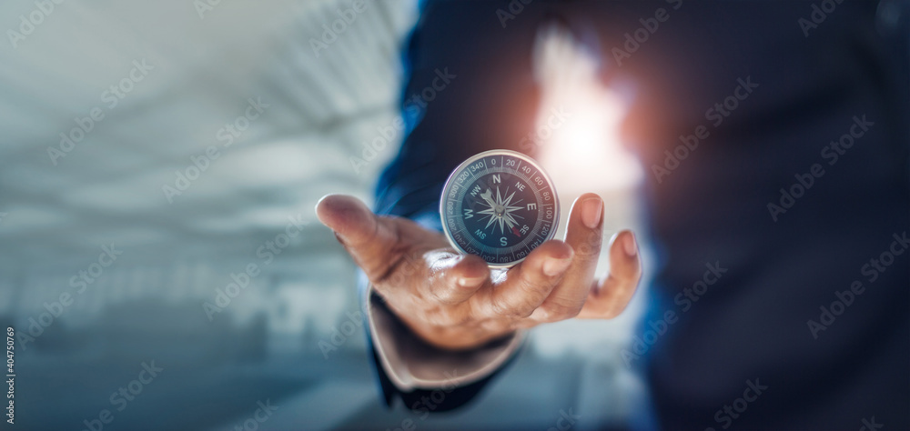 Fototapeta premium Businessman hand holding compass navigating business direction and successful strategic solution.Reflect accomplishment in terms of research and development growth market and financial profitability.