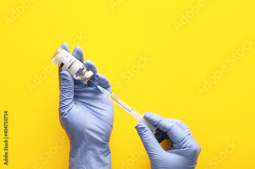 Doctor's hands with vaccine for immunization against COVID-19 on color background