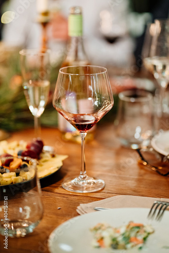 glass of wine on a wooden table during a festive candlelit dinner. romantic date. utensils for alcoholic beverages. Low light. Selective focus.