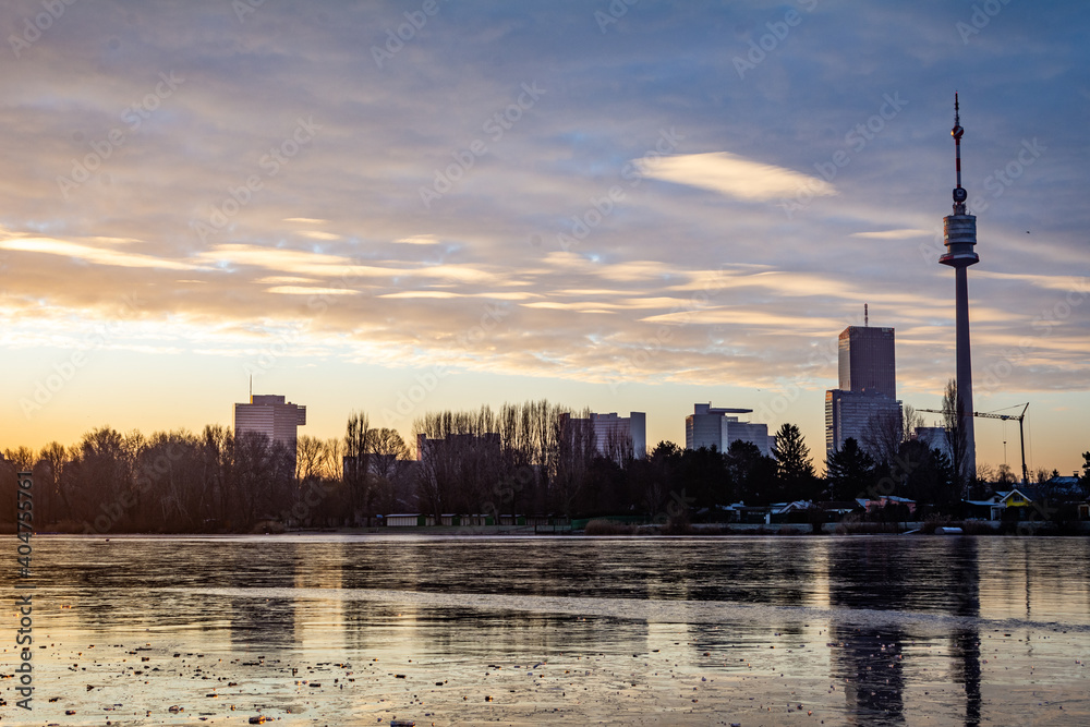 Beautiful morning scene at the so-called old Danube River in Vienna, Austria. View of a cold winter morning with a frozen lake and sun just above the horizon. Tranquil winter scene. 