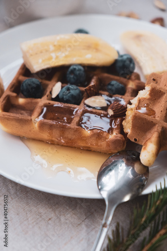 Breakfast with Belgian waffles with honey, blueberries, banana and almonds  on a linen tablecloth.  Vintage photo