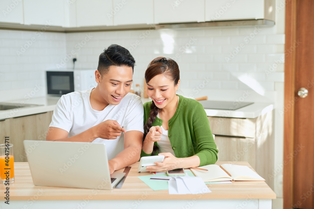 Photo of cheerful loving young couple using laptop and analyzing their finances with documents. Look at papers. Photo of cheerful loving young couple using laptop and analyzing their finances with documents. Look at papers.