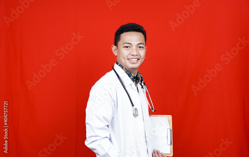Asian Male Doctor holding clipboard isolated red background