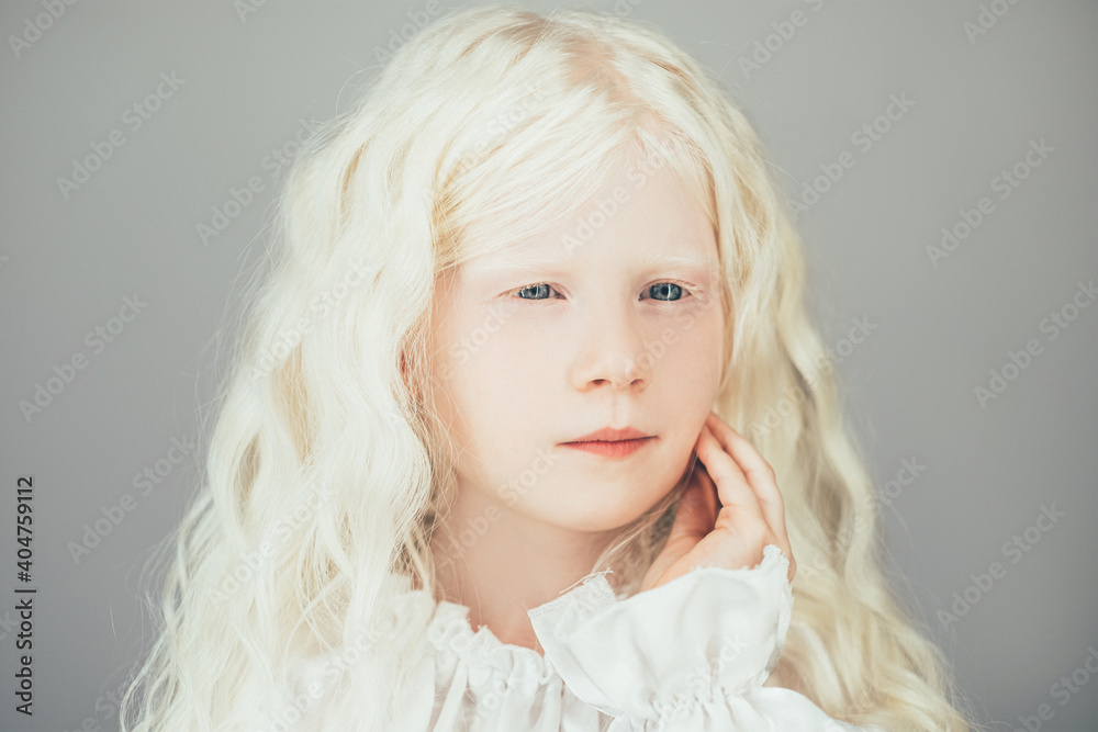 Albino beauty. Sweet child portrait. Pure innocence. Adorable thoughtful blonde small girl with white eyebrows curly hair blue eyes in vintage blouse isolated on gray background. Albino beauty. Sweet child portrait. Pure innocence. Adorable thoughtful blonde small girl with white eyebrows curly hair blue eyes in vintage blouse isolated on gray background.