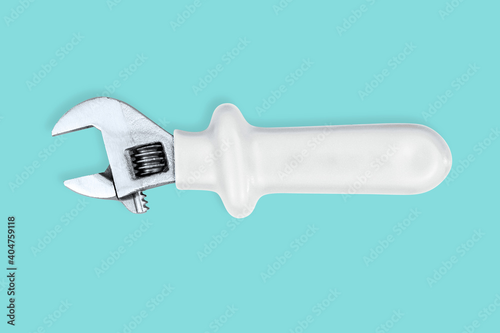 Adjustable metal wrench with rubberized handle on an aquamarine background. Adjustable metal wrench with rubberized handle on an aquamarine background.