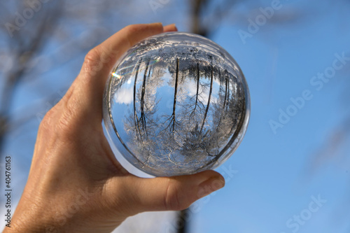 verschneiter Wald spiegelt sich in Glaskugel  die in der Hand gehalten wird  Naturerlebnis im Winter.