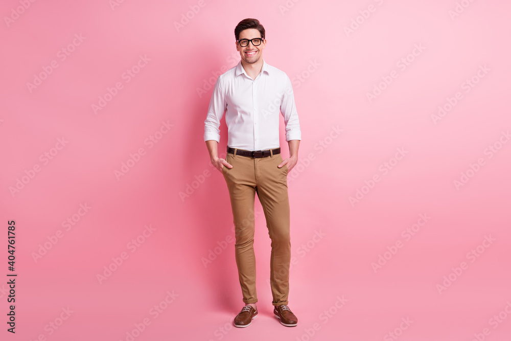 Full length photo portrait of representative man with hands in pockets isolated on pastel pink colored background Full length photo portrait of representative man with hands in pockets isolated on pastel pink colored background