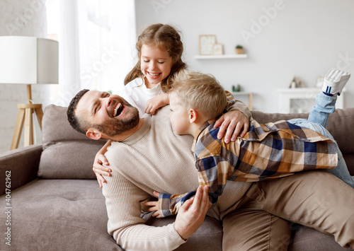 Photo Kids playing with father on sofa