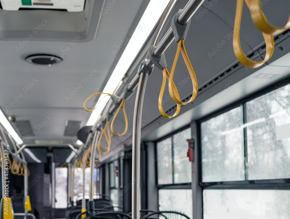 Interior of a empty bus with many hand holders or grips on the handle bar