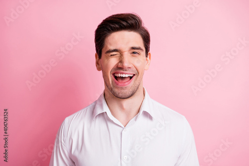 Portrait of optimistic guy blink wear white shirt isolated on pink color background