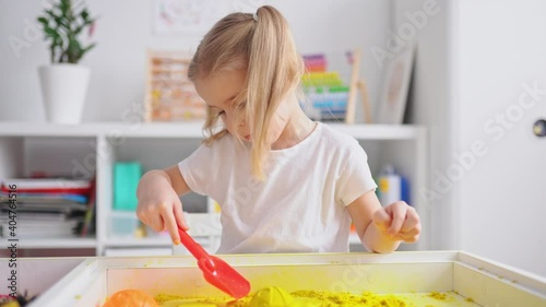 Little blonde girl with two ponytales play with magic sand. Development of fine motor skills, early education, sensorics photo