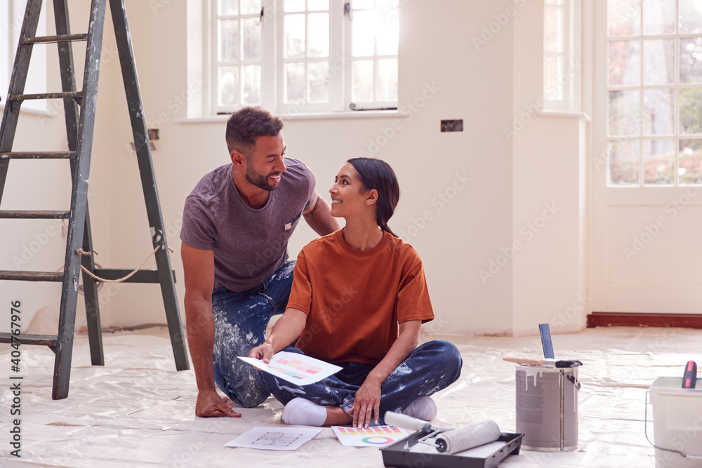 Couple Sitting On Floor With Paint Chart Ready To Decorate New Home Couple Sitting On Floor With Paint Chart Ready To Decorate New Home