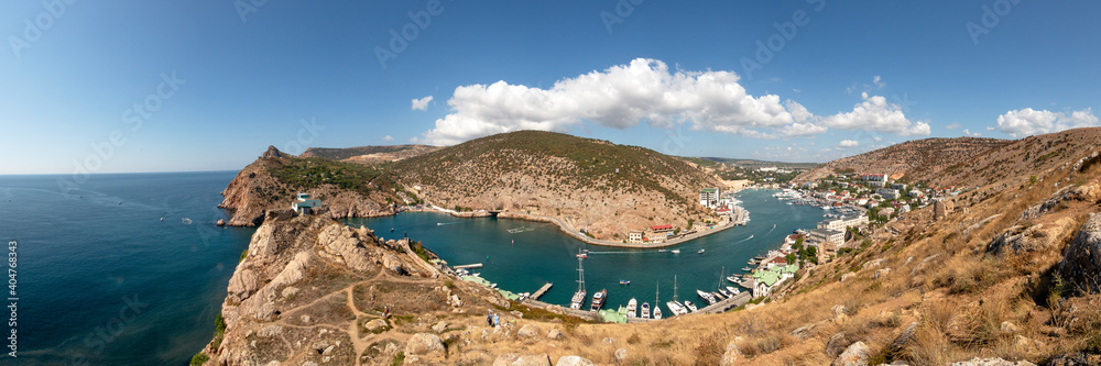 panorama of a curved bay with boats and buildings in the mountains