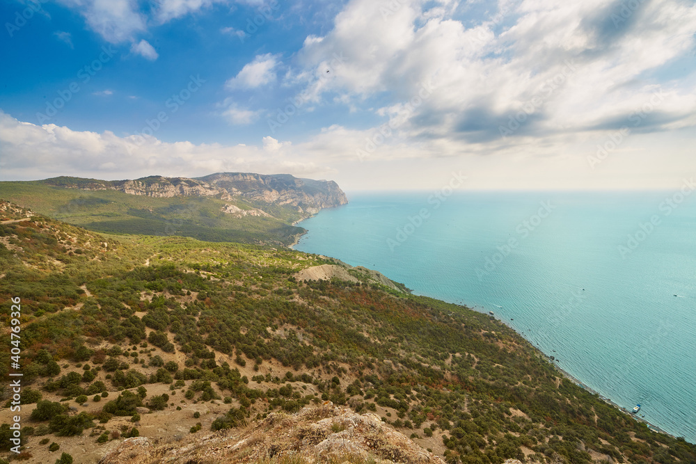 beautiful view of the coast with forest, mountains, blue sea and blue cloudy sky