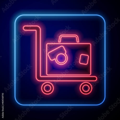 Glowing neon Hotel luggage cart with suitcase icon isolated on blue background. Traveling baggage sign. Travel luggage icon. Vector.