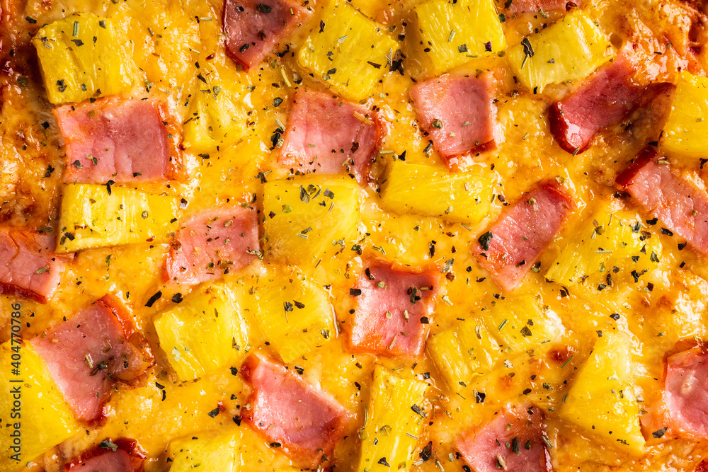 Just baked hawaiian pizza with freshly chopped pineapple and ham on the rustic wooden background. Selective focus. Just baked hawaiian pizza with freshly chopped pineapple and ham on the rustic wooden background. Selective focus.
