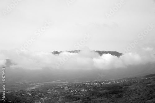 black and white view of the city and the mountain in the clouds