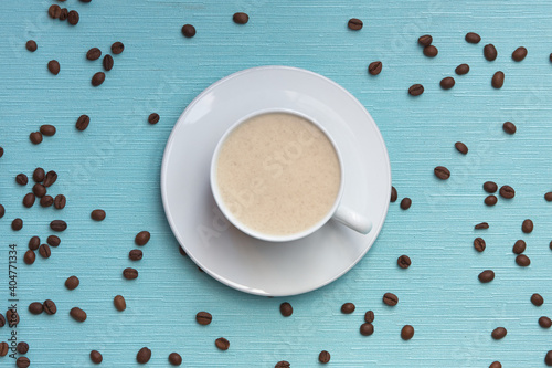 a cup of coffee on a blue textured background with scattered grains (ID: 404771334)