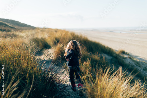 girl running in the dunes at the seacoast on sunset