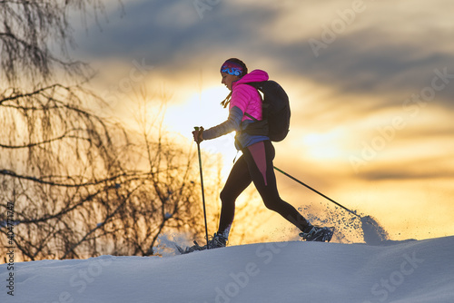 Lonely girl hike with snowshoes at sunset