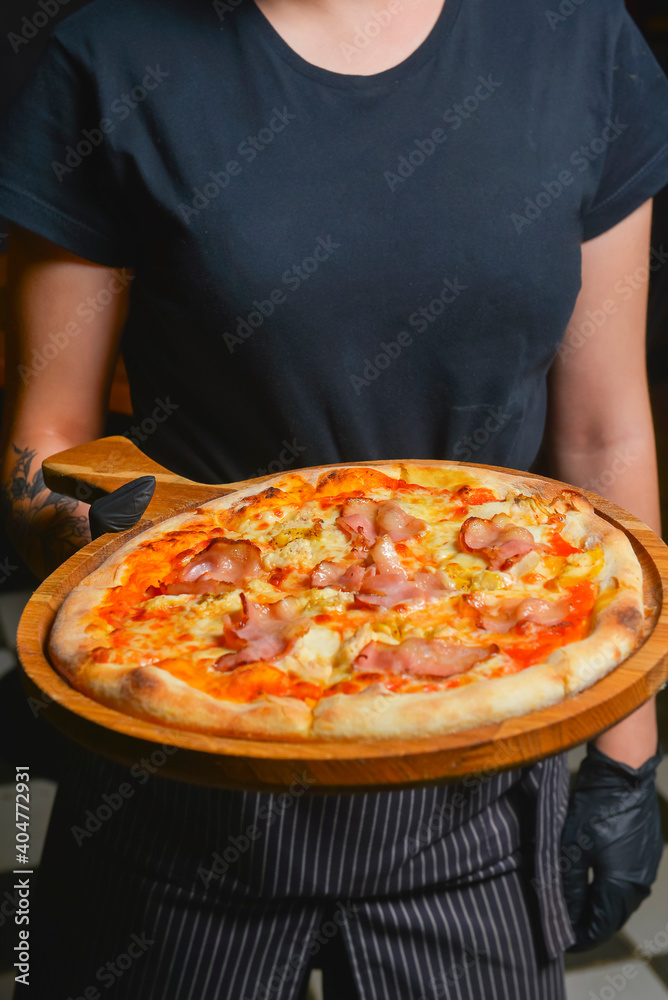 Waiter serving pizza Margherita in restaurant or diner, eating out concept, waiter at work. Fast food, junk food concept