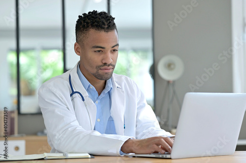 Portrait of general practitioner working in office in laptop