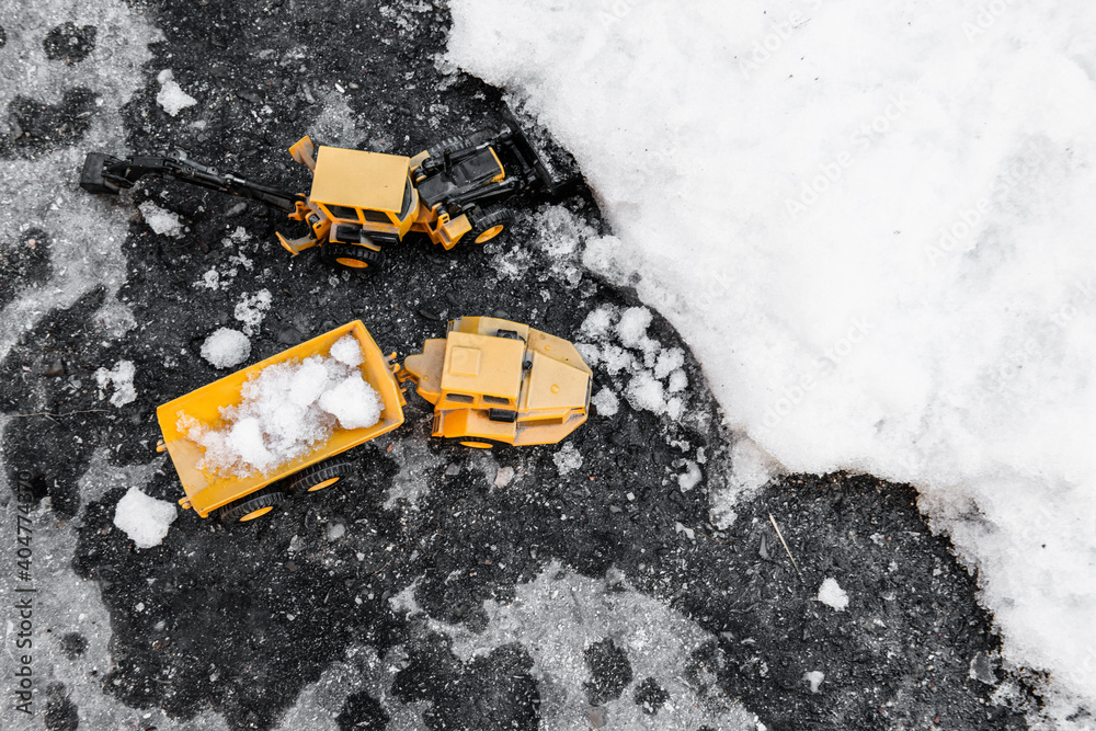 Top view of model excavators and cargo trucks collecting large amounts of snow after the winter storm. Problems with unfavorable weather conditions