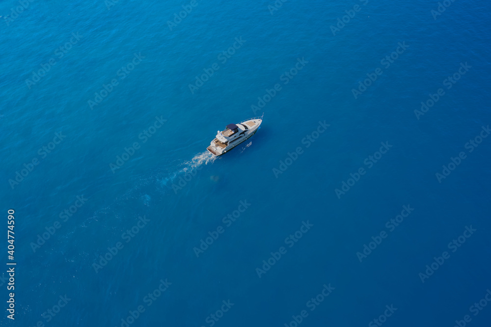 Aerial view of a white yacht on blue water. luxury motor boat. Top view of a white boat sailing in the blue sea. Drone view of a boat.