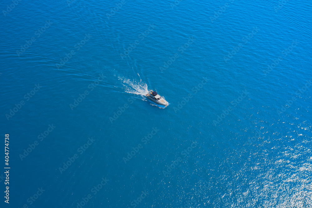 Aerial view of a white yacht on blue water. Top view of a white boat sailing in the blue sea. Drone view of a boat. luxury motor boat.