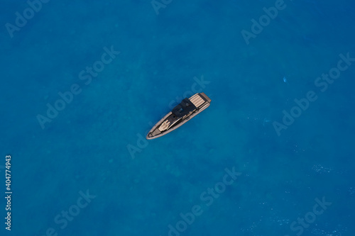 Lonely boat mooring on the water. luxury motor boat. Drone view of a boat. Top view of a white boat in the blue sea. Aerial view of a yacht on blue water. © Berg