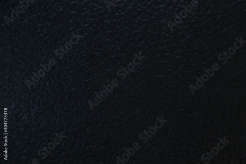 Blurred black glass surface with frozen water drops close up after icy rain, abstract winter texture for background