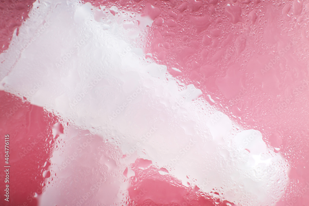 Fototapeta premium moisturizing skin care products. Face and hand cream under a glass surface with water on a pink background. spa cosmetic