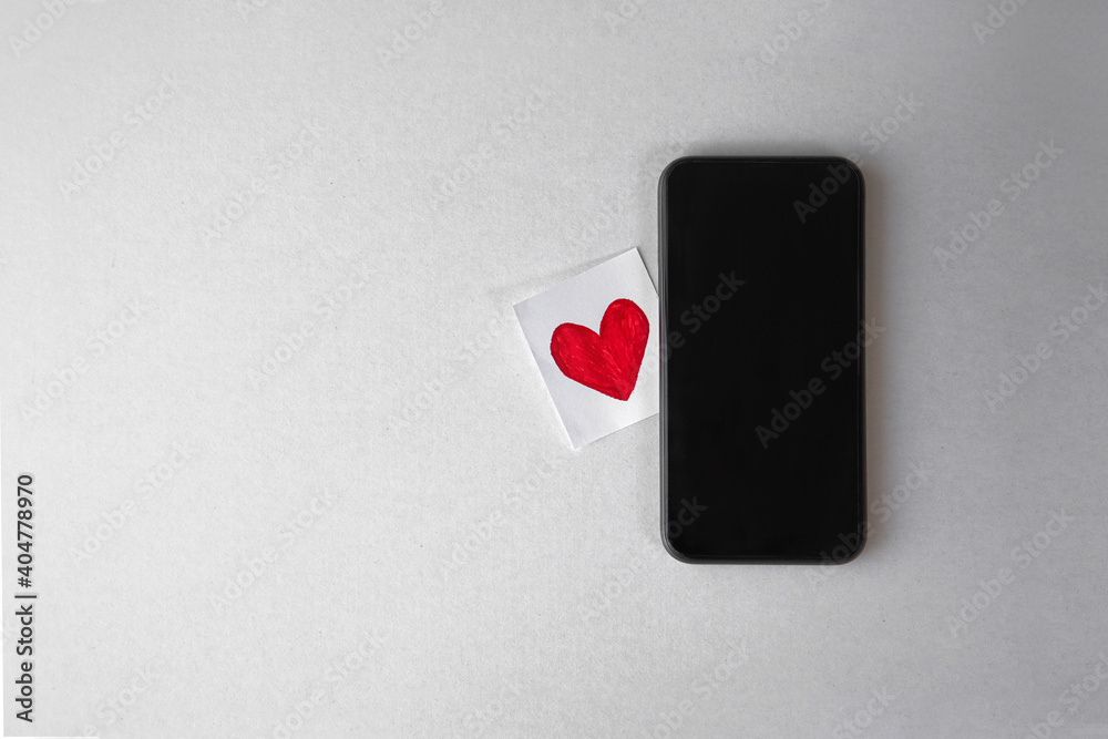 Mockup top view phone next to sliced of white paper hand draw love heart on grey white paper background with copy space