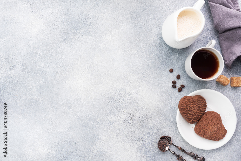 Chocolate heart cookies and a cup of black coffee with milk on the table, top view. Copy space. Chocolate heart cookies and a cup of black coffee with milk on the table, top view. Copy space.