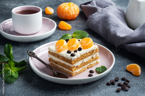 Sponge cake layers with buttercream, decorated with slices of tangerine chocolate and mint. Delicious sweet dessert for tea.