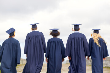 education, graduation and people concept - group of international graduate students in mortar boards and bachelor gowns outdoors